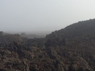 A cloud reduces visibility on Mauna Loa on the island of Hawaii. Vegatation is sparse on the mountain slopes.