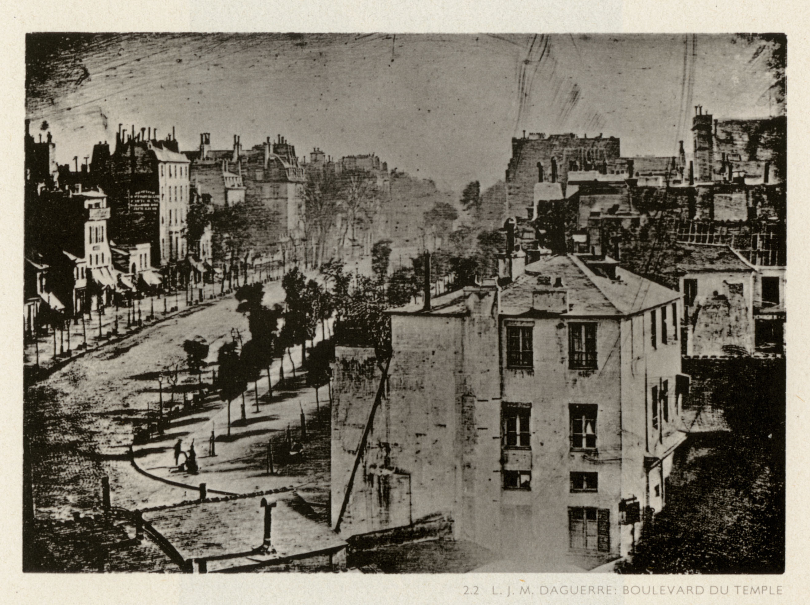A historic black-and-white daguerreotype photograph capturing an elevated view of a building-lined Paris street