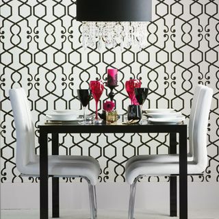 black dining room table with white chairs geometric print wallpaper and black ceiling light