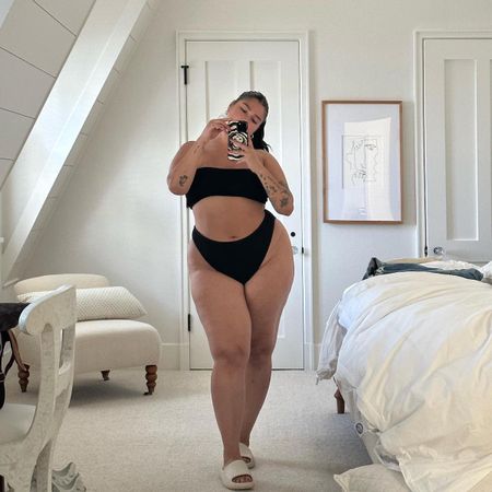 Woman taking a mirror selfie wearing a black swimsuit