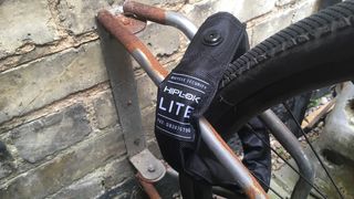 A Hiplok LITE wearable chain lock securing a bike to a wall-mounted rack