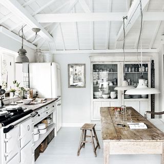 kitchen with white wall and wooden table and fridge