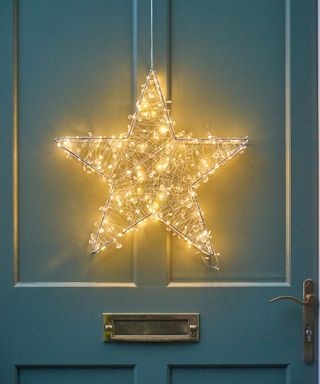 A lit up star hung on a front door