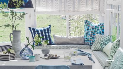 White conservatory with blue and white cushions on a window seat around a dining table