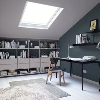 attic room with grey wall and desk and chair and bespoke shelving unit and wooden floor
