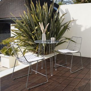 modern grey metal bistro set with a glass topped table on a modern balcony