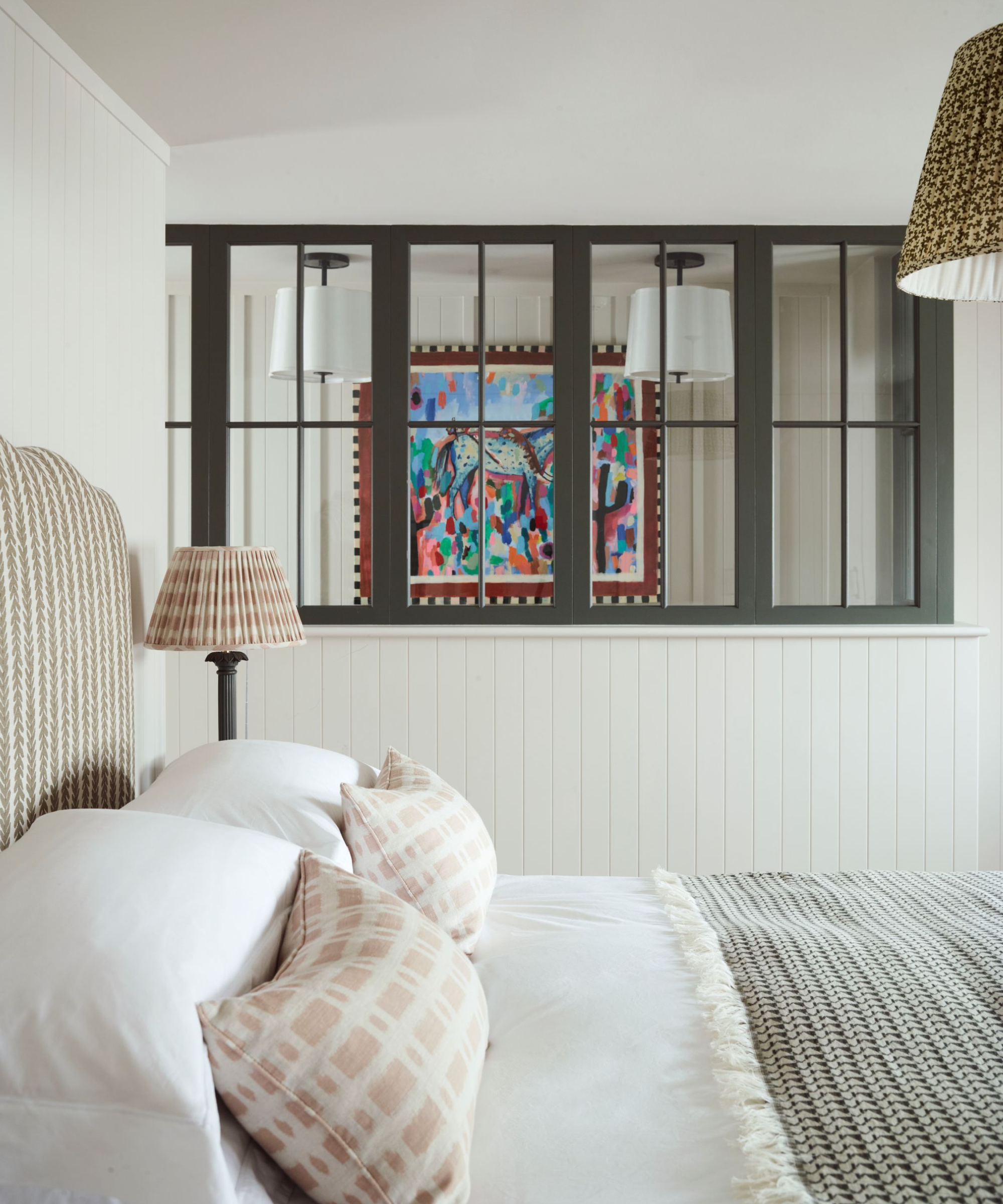a bed in a room with windows looking into another room