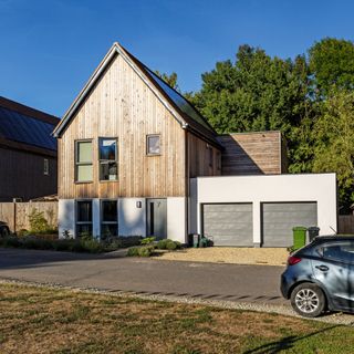 Modern panelled front of house exterior with lawn and car parked