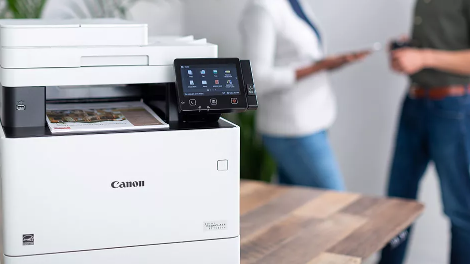A Canon printer with two people in the background.