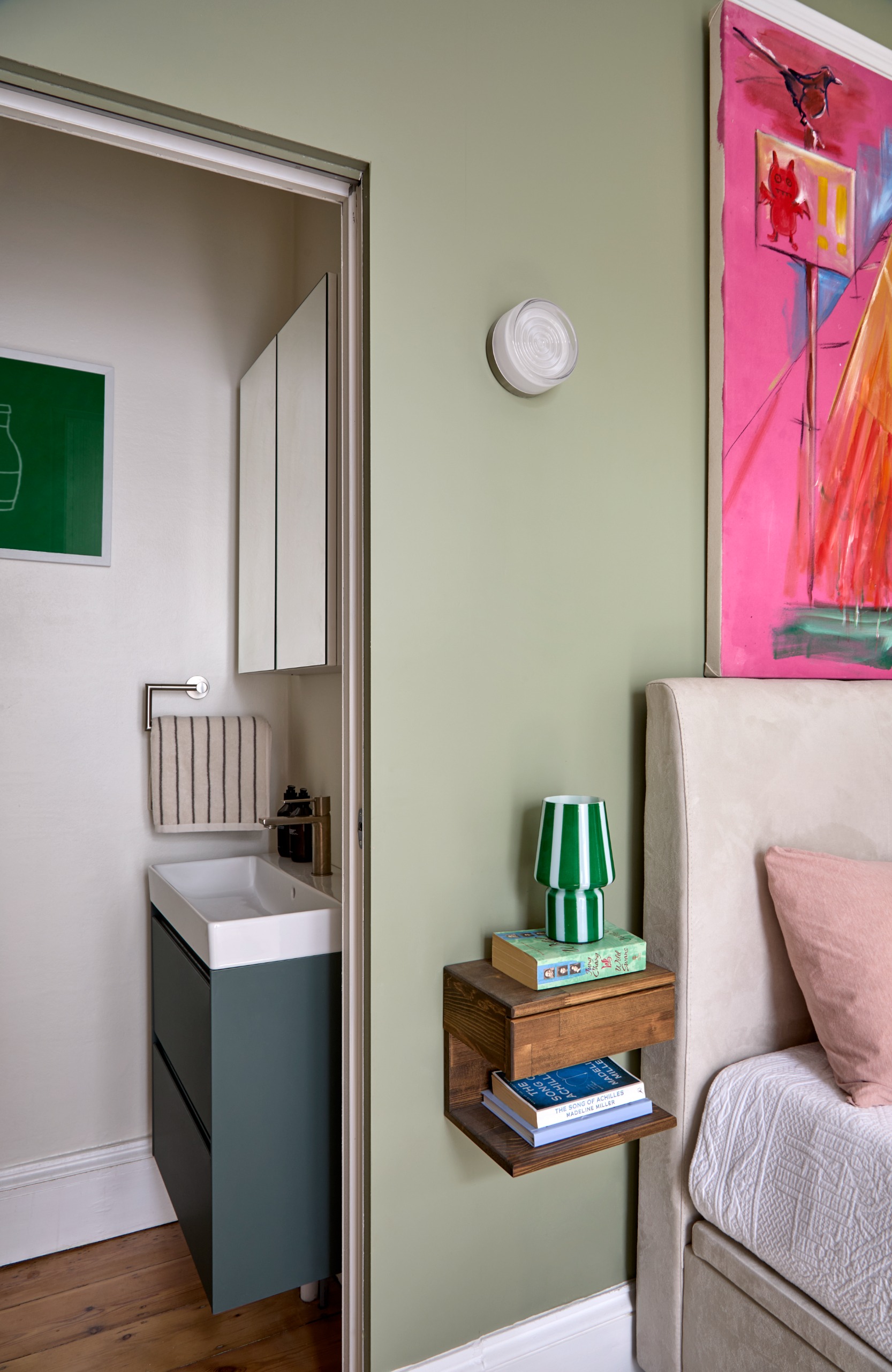 bedroom with sage walls, and floating bedside tables, and a small ensuite to the side of the bed