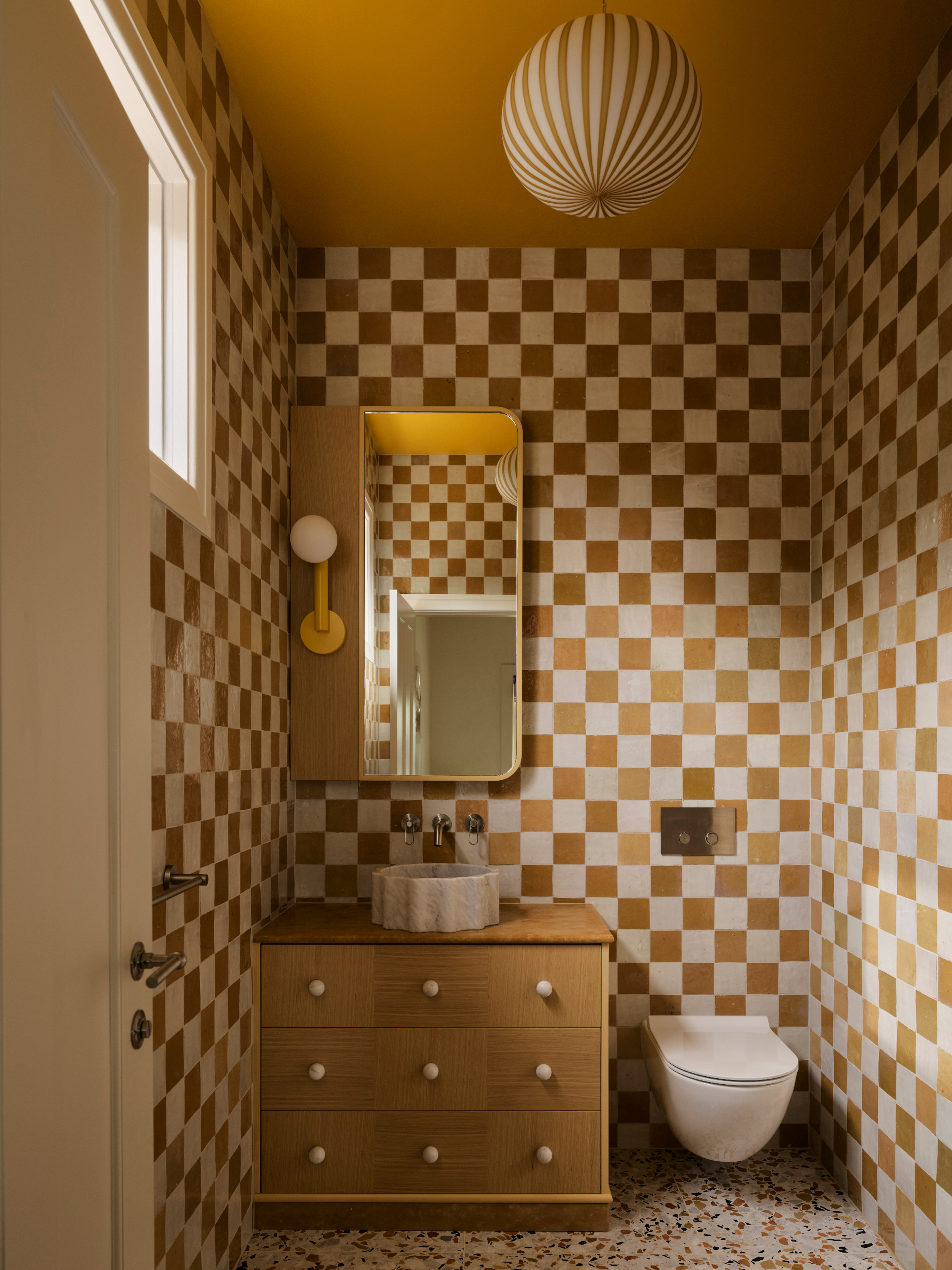 Bathroom with mustard and white checkerboard tiles, wood vanity and oversized mirror