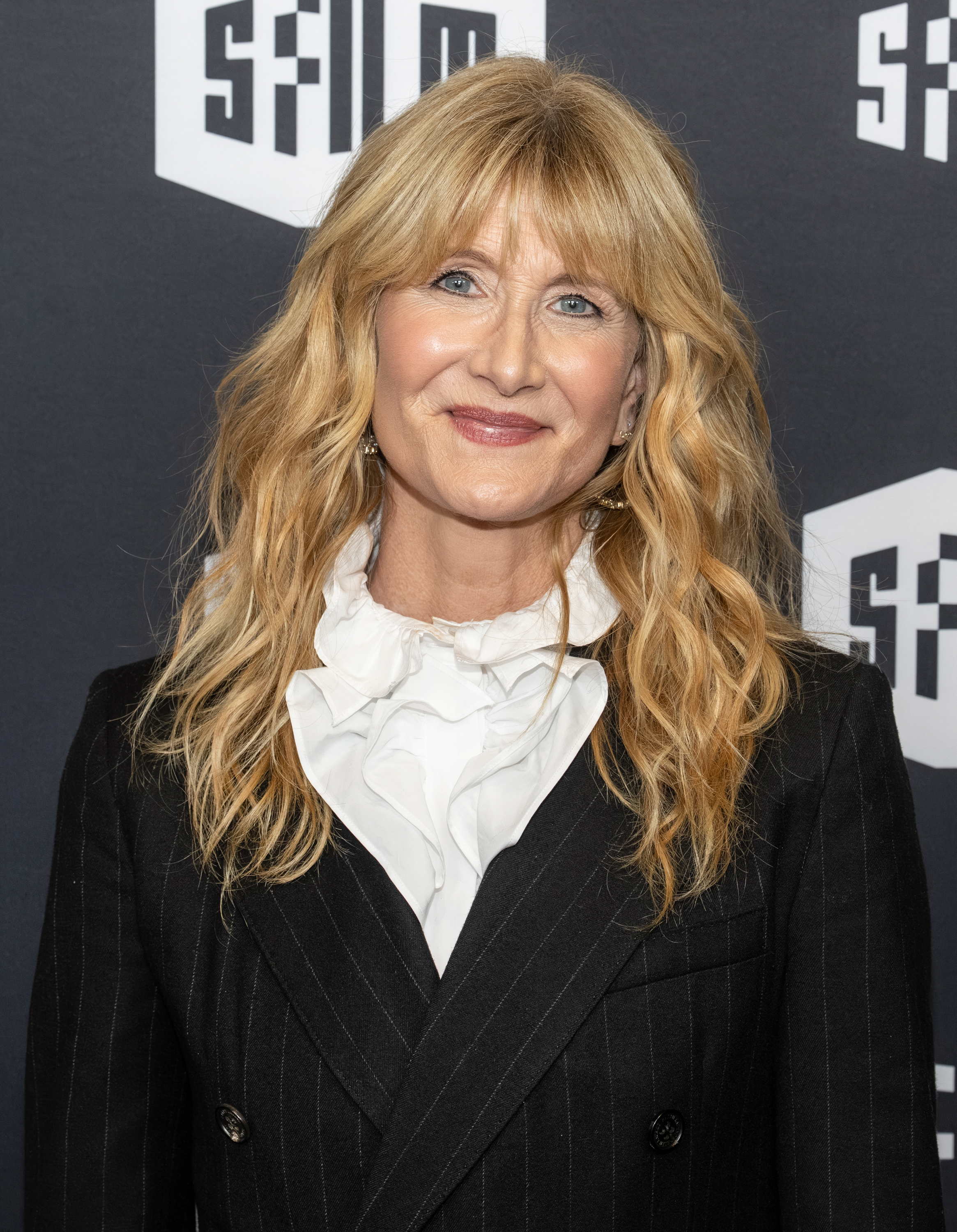 a white woman with wavy, blonde hair and curtain bangs