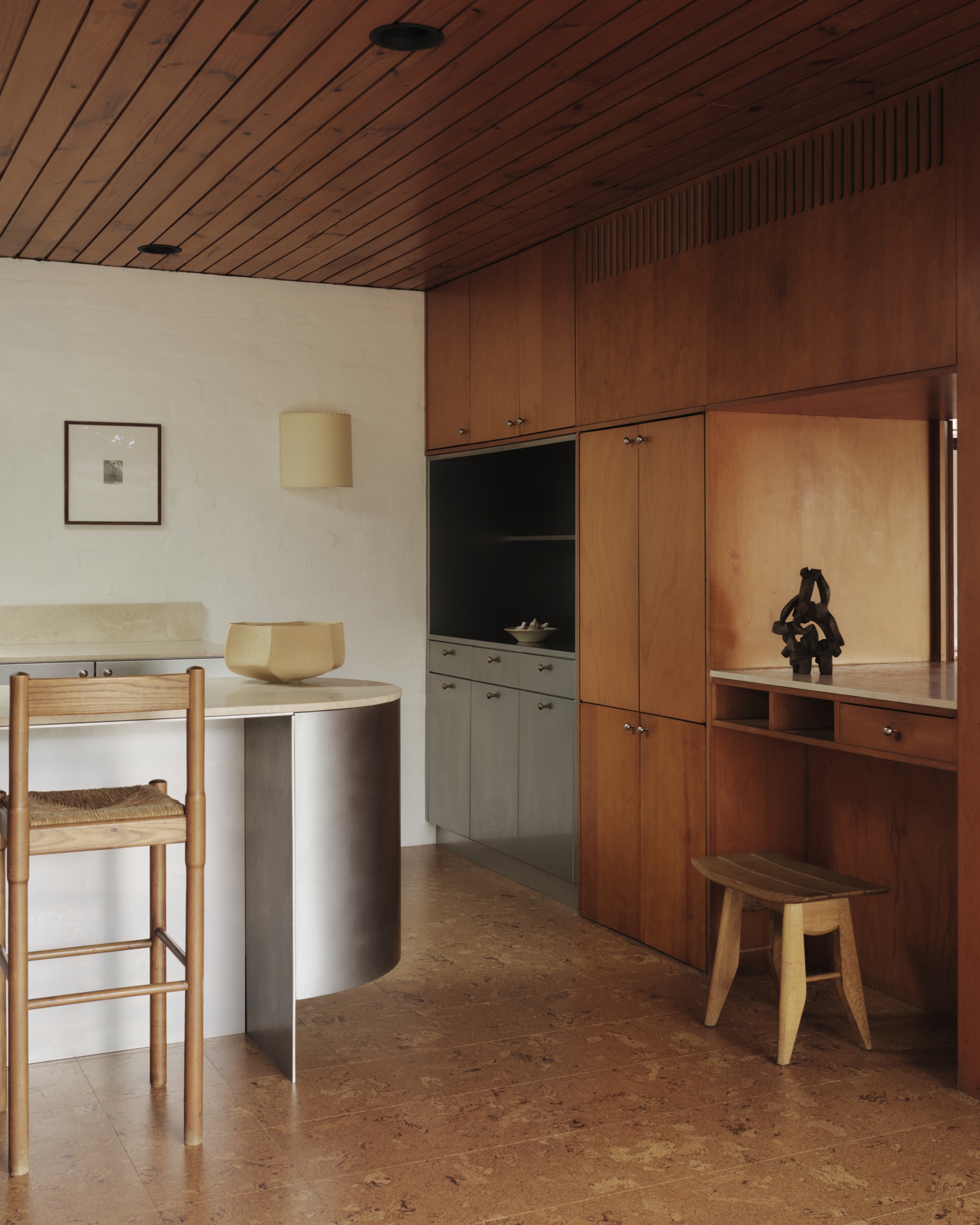 a wood kitchen with a rounded steel island and inset cabinets, and a panelled ceiling