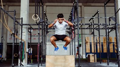 Man doing a box jump in a crossfit gym