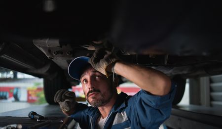 Car repair mechanic working underneath a car.