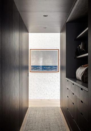 dark wooden walk-in closet with white exposed brick wall