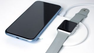 Apple gadgets, products charging on a wireless charger.