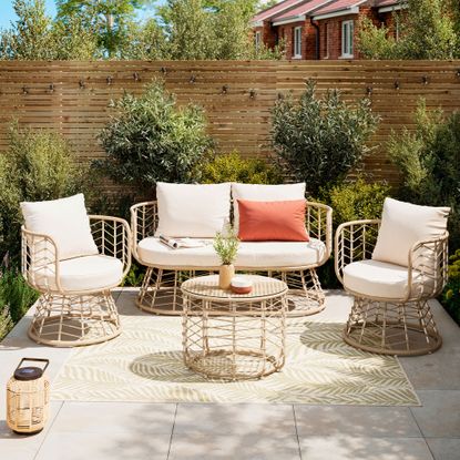 Patio set with beige cushions and coffee table on small patio with wooden fence