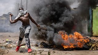 A protester throws a stone towards police in Nairobi