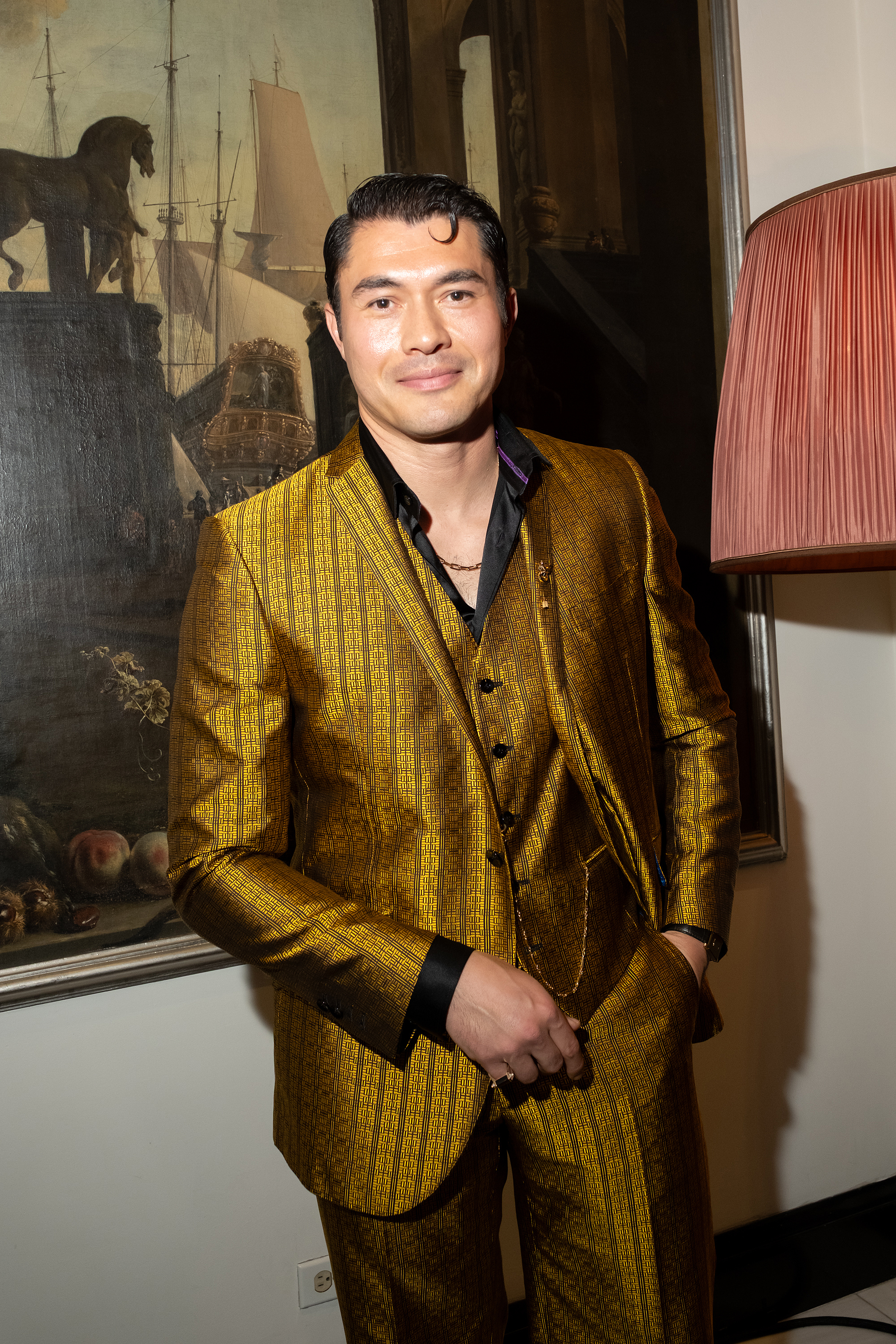 Henry Golding wearing a kiss curl hairstyle.