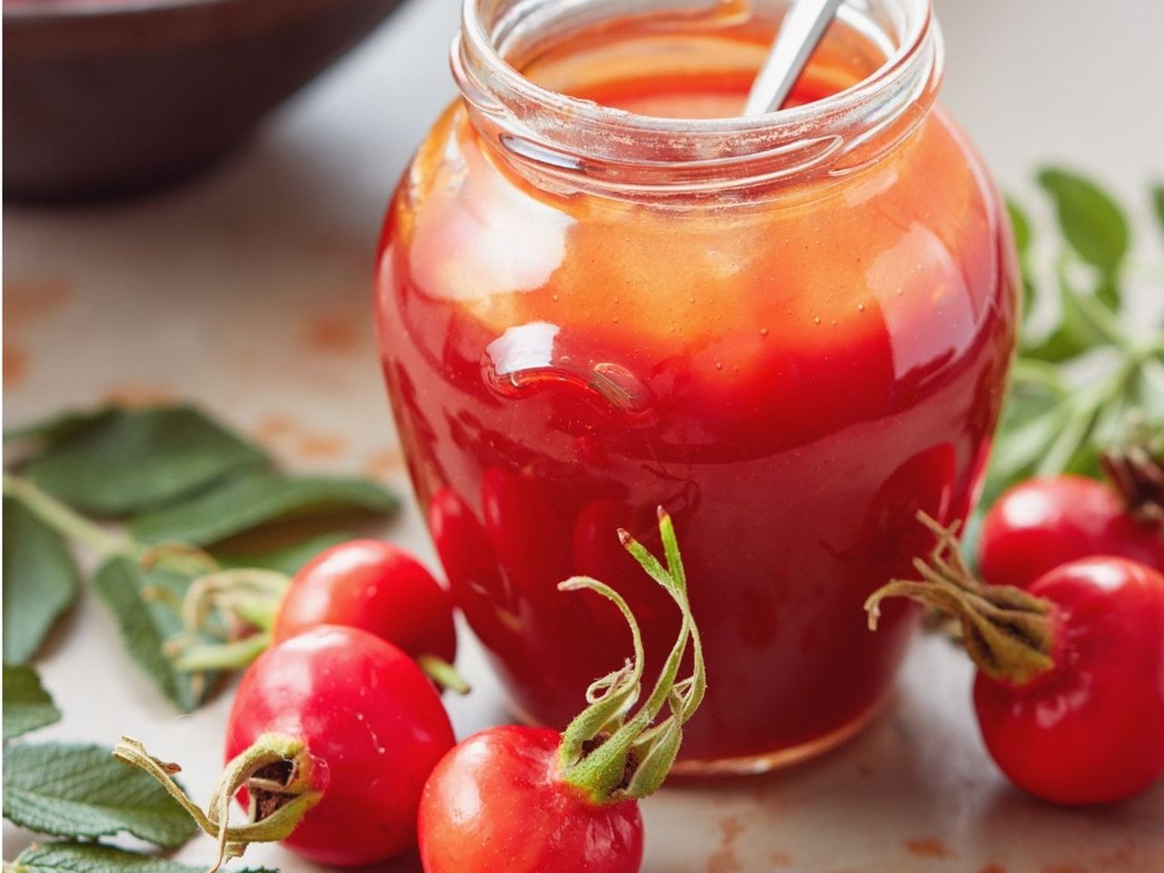 Fresh Rose Hips Next To A Jar Of Jelly