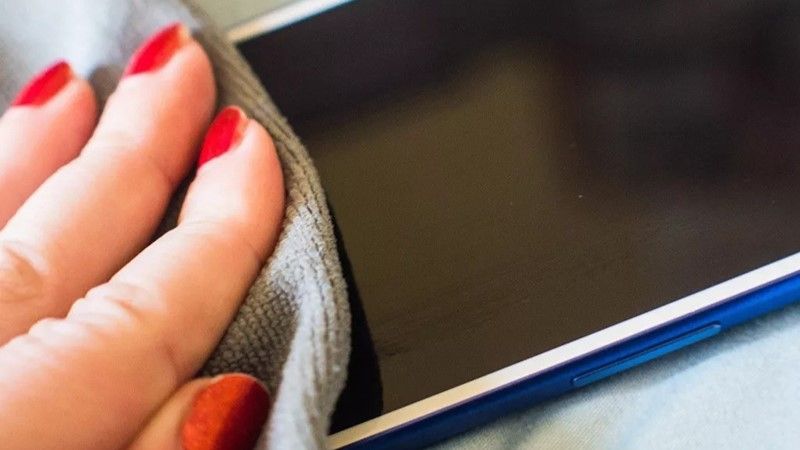 A hand cleaning a phone with a microfiber cloth