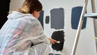 woman crouching down looking at paint samples on wall