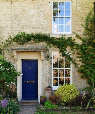 A stone cottage with blue door and ivy