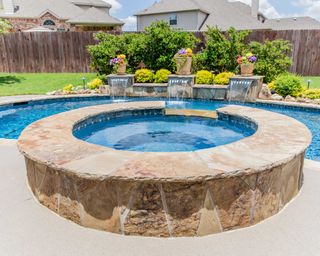 hot tub with stone surrounding near pool