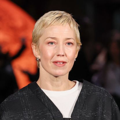 a white woman with a short, blonde haircut poses for paparazzi during a fashion week event