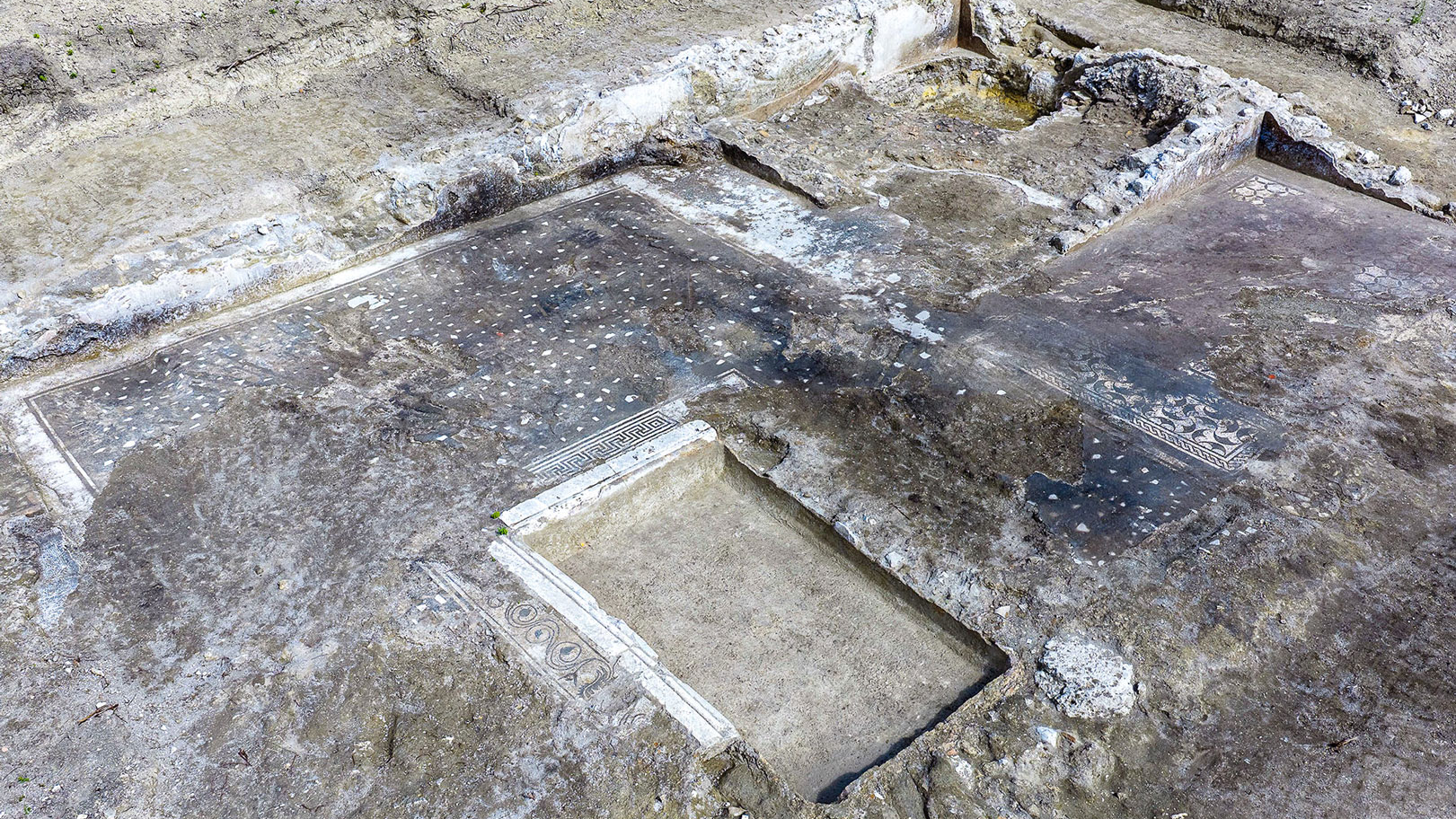 archaeologists work at an ancient Roman site revealing mosaic floors and frescoed walls of a villa