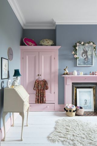 Blue children's room with pink painted wardrobe and fireplace, white painted floorboards and a cream bureau