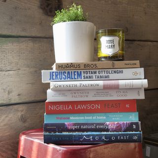 stack of books white plant pot and wooden wall