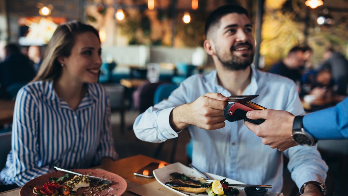 A man and woman paying for food at a restaurant using a contactless VISA card 