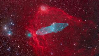 a large red gaseous looking cloud of dust and gas surrounds a blue hued cloud shaped like a squid. to the left of the squid is a greeny blue sphere of light. 