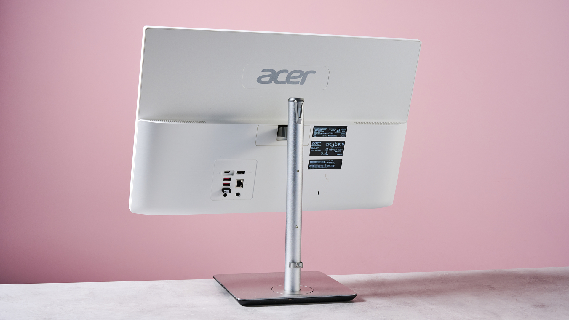 Back of Acer Aspire C24, on desk against a pink background