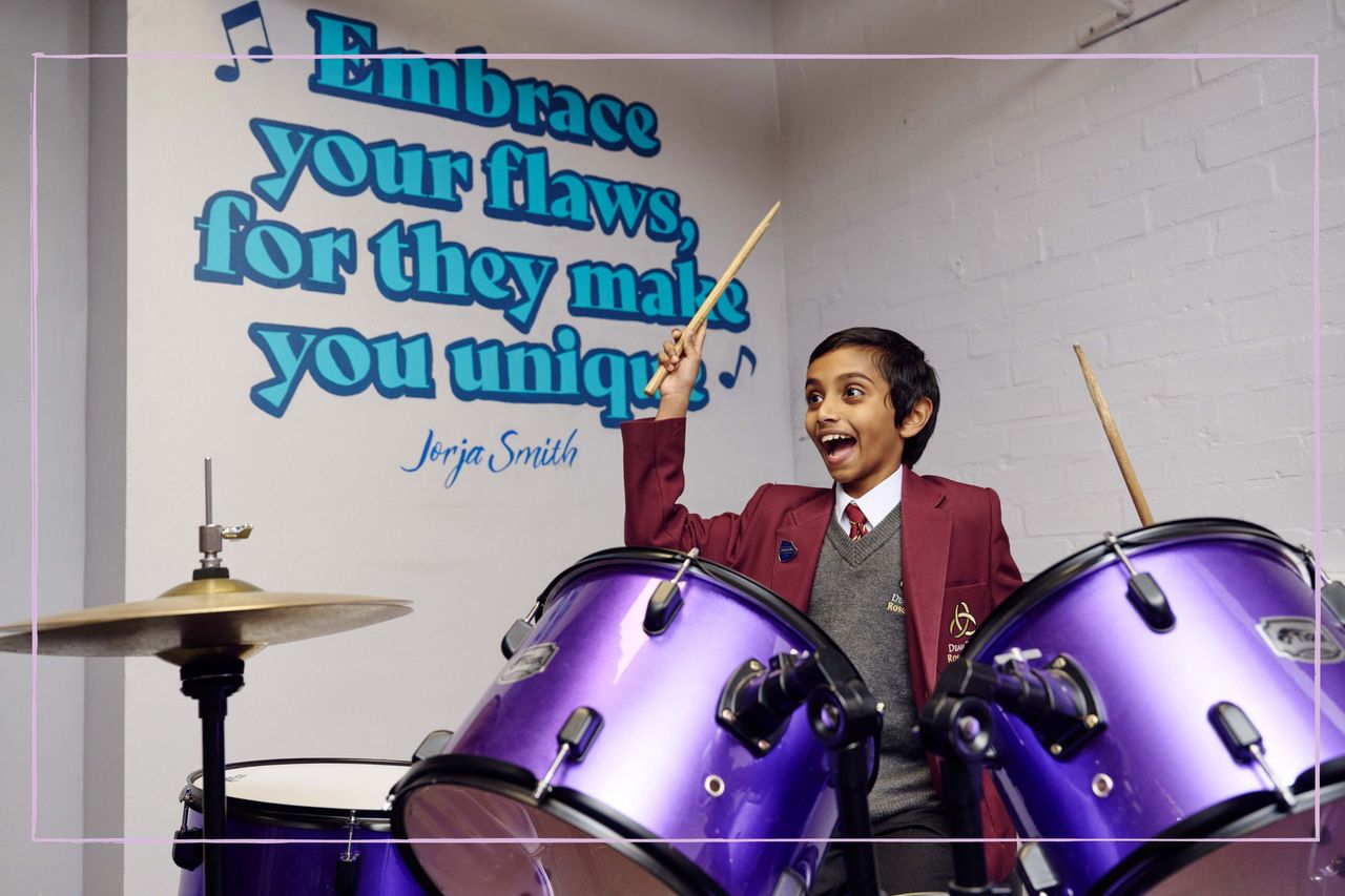 A boy playing the drums in front of a wall with the quote &#039;Embrace your flaws, for they make you unique&#039;