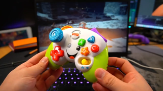 An image of a toy Fisher-Price controller modified to be a functional controller. It is displayed in front of a gaming laptop running Elden Ring. The controller is bright primary colors.
