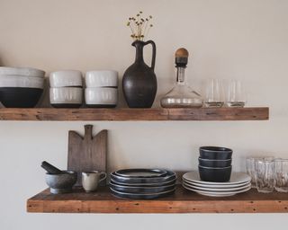 Floating shelves with nested brown or cream dishes and mugs