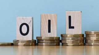 wooden blocks spelling out word oil on top of rising piles of coins