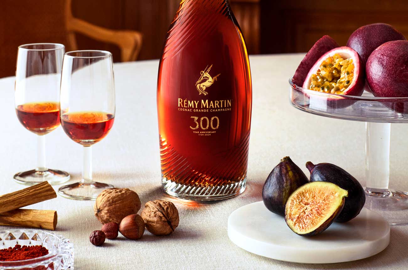 Figs and nuts on a white tablecloth with a bottle of R&amp;eacute;my Martin 300th Anniversary Coupe