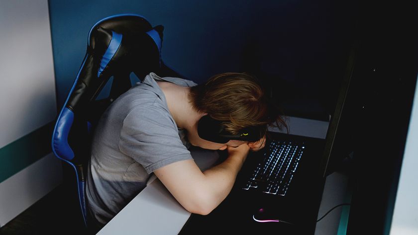 Man upset at gaming PC, resting head on arms