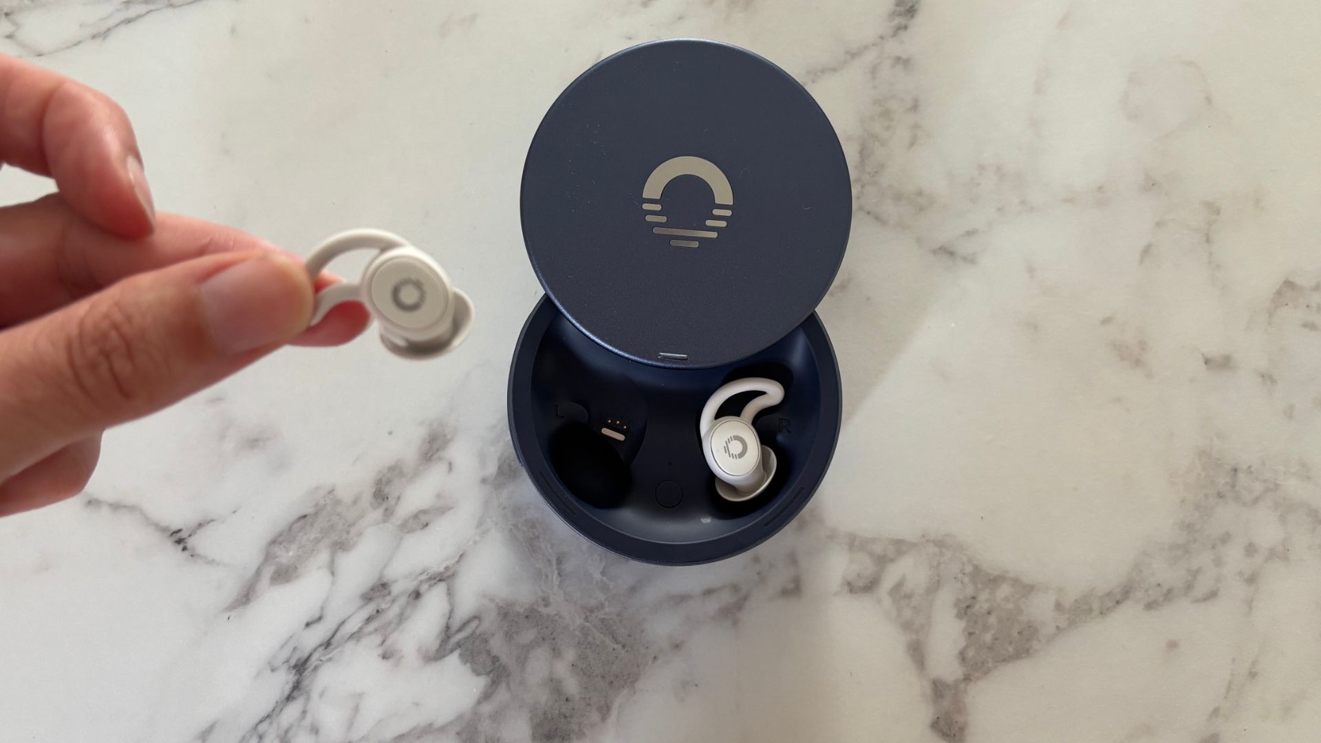 The image shows the Ozlo Sleepbuds 2 in their blue case on a marble worktop