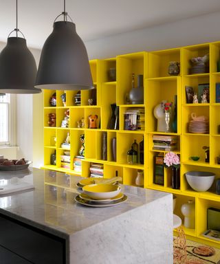 An example of kitchen shelving ideas showing a large yellow kitchen storage unit with open shelving