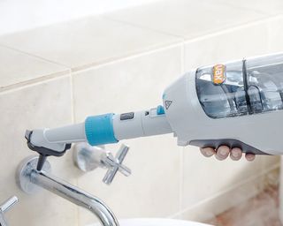 Image of Vax steam cleaner beig used on bathroom taps