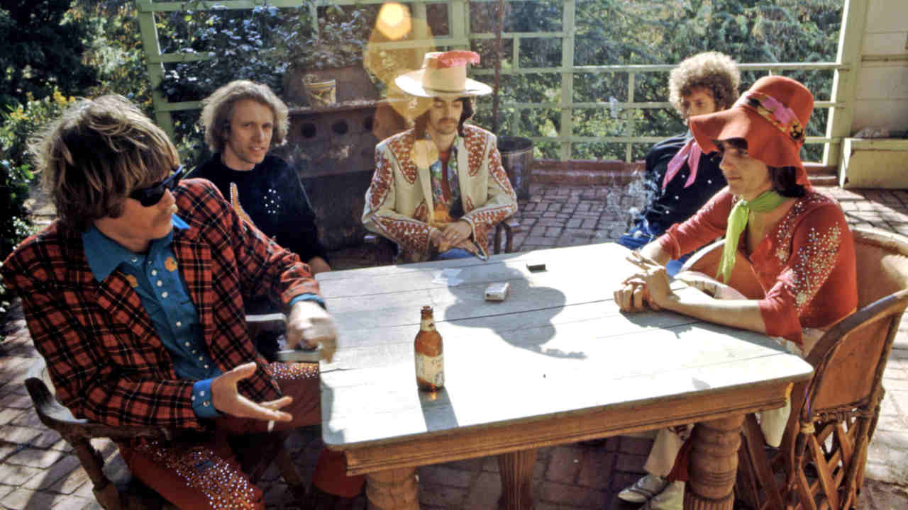 The Flying Burrito Brothers playing cards at a table in a sunny backyard
