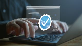A stylized image of an unidentified person using a laptop and pressing a digital image of blue tick checkmark floating in the air.