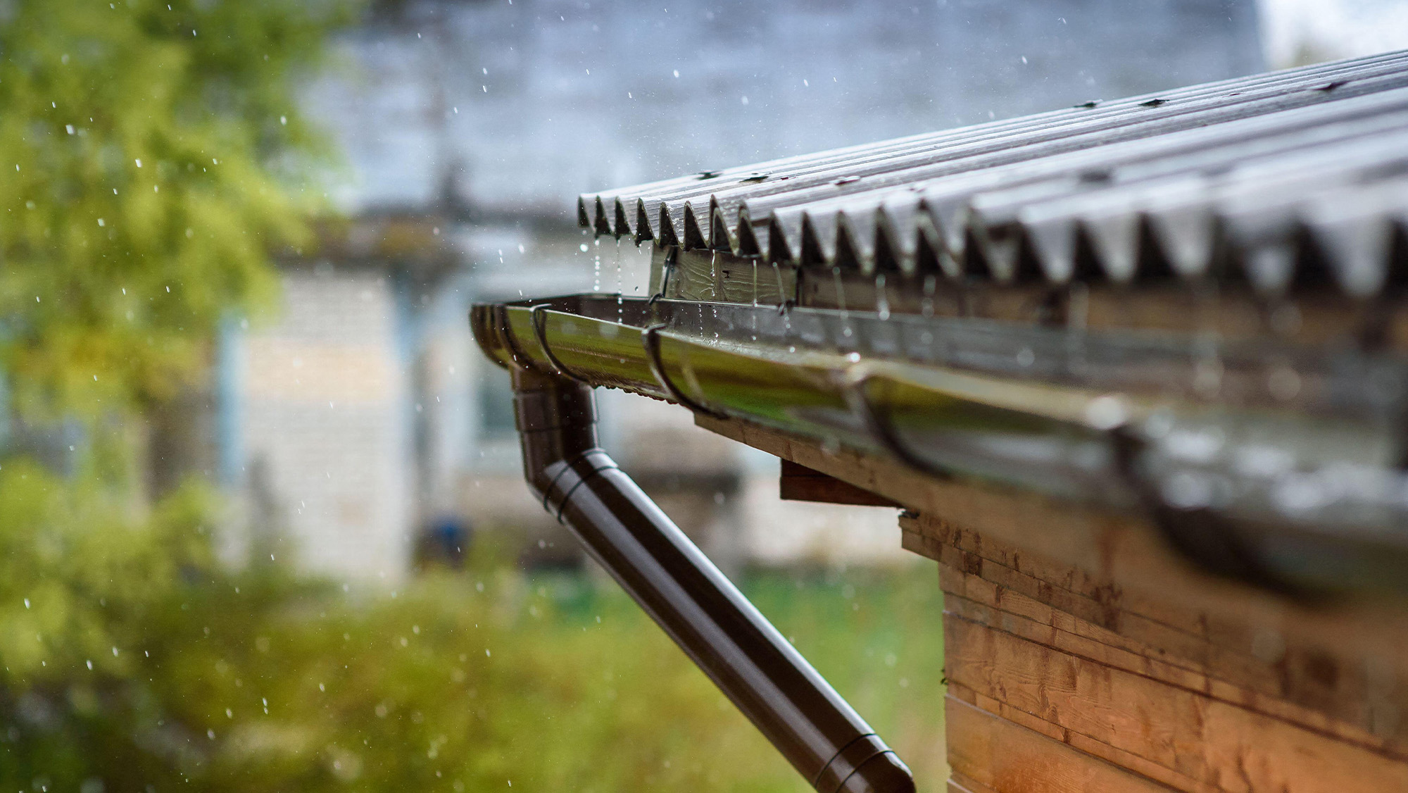 Rain running off stable roof into gutter as part of rainwater harvesting system