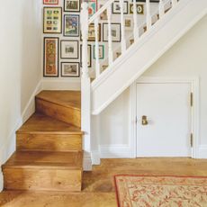 Hallway and staircase with wooden floors and a gallery wall up the stairs