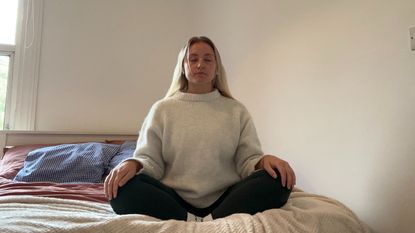 Woman meditating on bed in cross-legged position